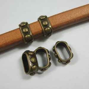 May include: Three antique gold-toned metal cord ends with a decorative design of small circles. The cord ends are designed to be used with leather cord.