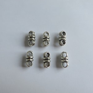 May include: Six silver metal connector beads for jewellery making. Each bead has two loops.