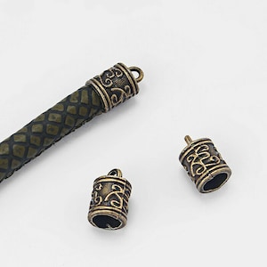 May include: Three antique gold-toned metal cord end caps with an ornate design. The end caps are used for leather cord or rope.