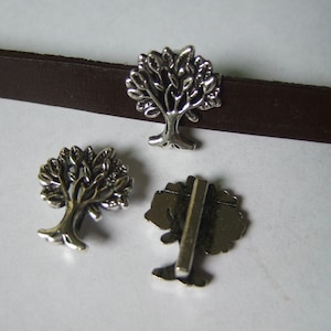 May include: Three silver metal tree-shaped charms. The charms are detailed with intricate branches and leaves. The charms are suitable for jewelry making or other craft projects.