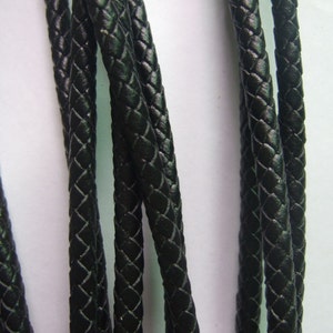 Puede incluir: Primer plano de un cordón de cuero trenzado negro. El cordón está tejido en forma de diamante y tiene un acabado liso y pulido.