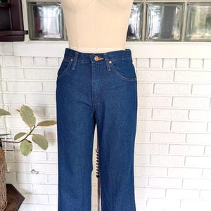 K&ouml;nnte beinhalten: Eine dunkelblaue Jeans mit geradem Bein. Die Jeans hat eine hohe Taille und einen klassischen F&uuml;nftaschen-Stil.