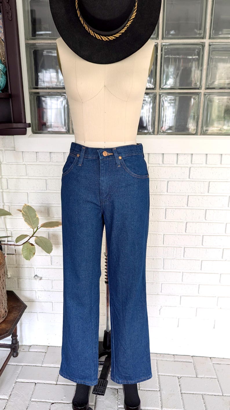 K&ouml;nnte beinhalten: Eine dunkelblaue Jeans mit geradem Bein. Die Jeans hat eine hohe Taille und einen klassischen F&uuml;nftaschen-Stil.