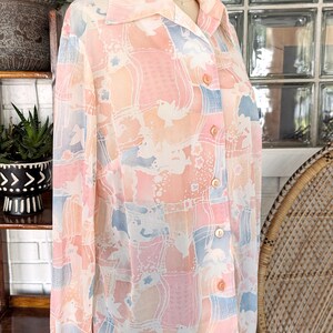 Peut inclure: Une chemise &agrave; manches longues boutonn&eacute;e avec un imprim&eacute; abstrait rose, bleu et blanc. La chemise est en tissu transparent et a un col.
