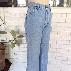 K&ouml;nnte beinhalten: Hellblaue Jeans aus Denim mit hoher Taille und gerader Beinweite. Die Jeans haben einen Knopfverschluss und G&uuml;rtelschlaufen.
