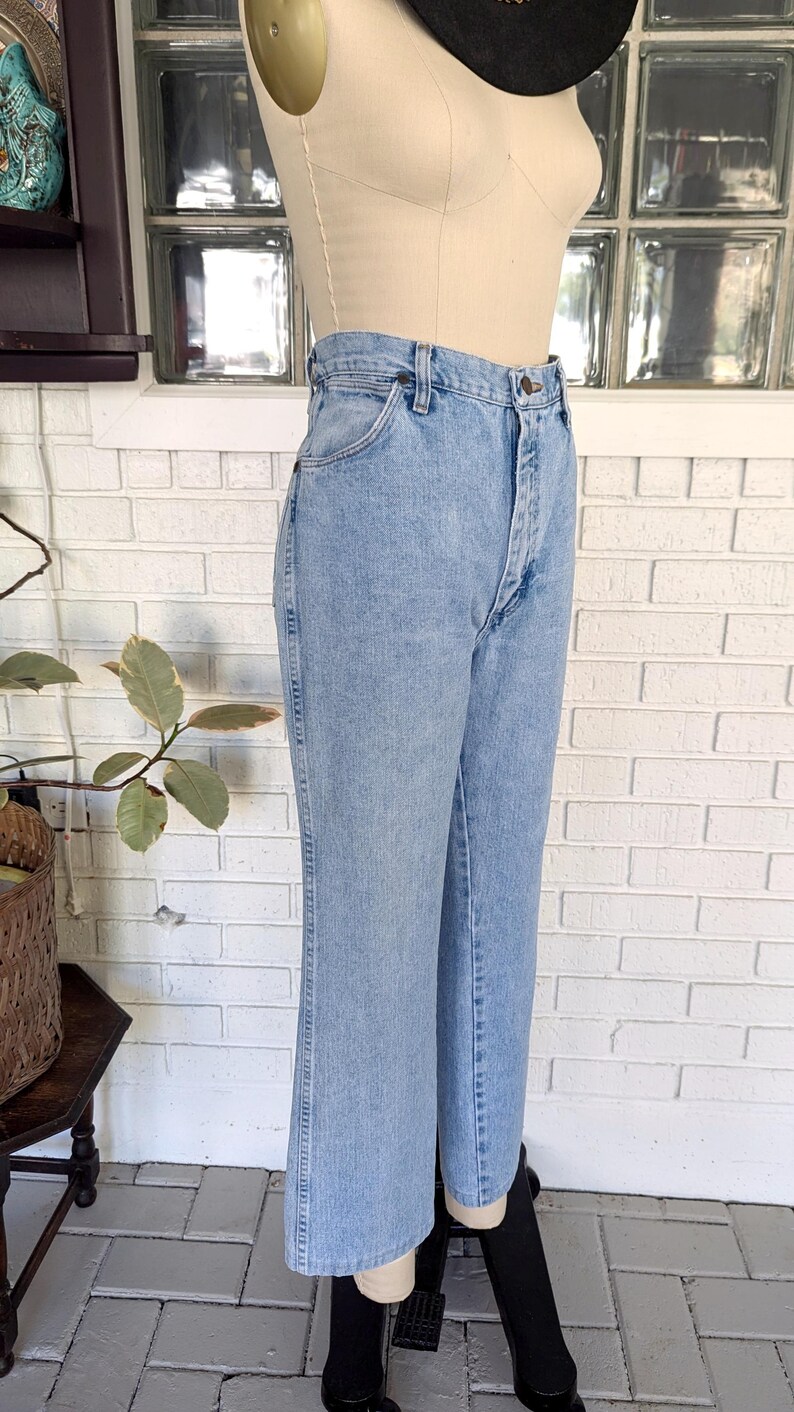 K&ouml;nnte beinhalten: Hellblaue Jeans aus Denim mit hoher Taille und gerader Beinweite. Die Jeans haben einen Knopfverschluss und G&uuml;rtelschlaufen.