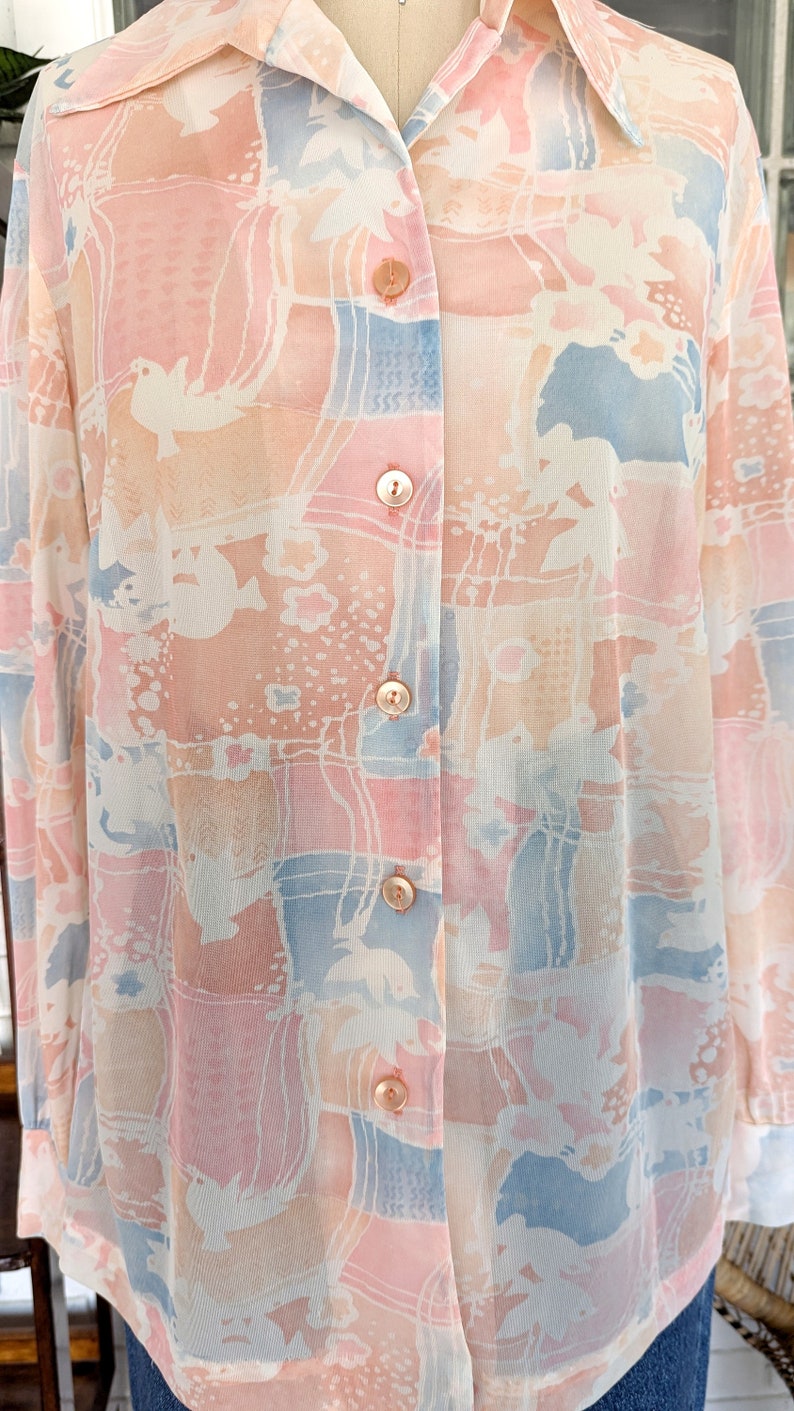 Peut inclure: Une chemise &agrave; manches longues &agrave; boutons avec un imprim&eacute; abstrait rose p&acirc;le, bleu et blanc.