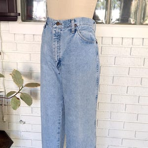 K&ouml;nnte beinhalten: Hellblaue Jeans aus Denim mit hoher Taille und geradem Bein. Die Jeans haben einen Knopfverschluss und f&uuml;nf Taschen.