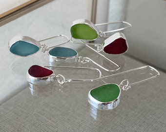 Könnte beinhalten: Fünf Paar silberne Ohrringe mit verschiedenen farbigen Meerglassteinen. Die Steine sind in Grün-, Blau- und Rottönen.