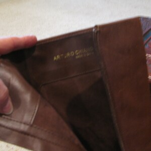 May include: Close-up of the inside of a brown leather boot with the text "ARTURO  GHIRARDI  MADE IN ITALY" in gold lettering.