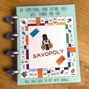 May include: A light blue and green board game with a cartoon character holding money bags. The game is called "Savopoly" and has a title that reads "Do something - your future self will thank you for". The game board has spaces for rolling dice and saving money.