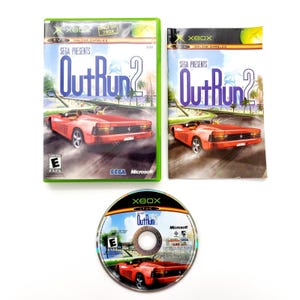 以下が含まれることがあります： 「OutRun 2」のXboxビデオゲームセット。ゲームケース、カバーアート、ディスクが含まれています。カバーアートには、海岸道路を走る赤いスポーツカーが描かれています。ゲームはセガとマイクロソフトによって公開されています。