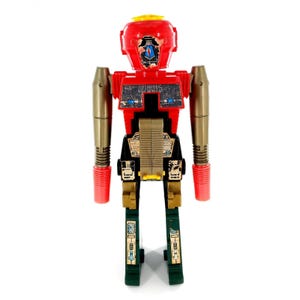 Könnte beinhalten: Ein Vintage-Spielzeugroboter mit rotem Kopf und Torso, goldenen Armen und grünen Beinen. Der Roboter hat ein gelbes Kopfteil und rote Hände und Füße. Die Brust des Roboters hat ein schwarzes und silbernes Design.