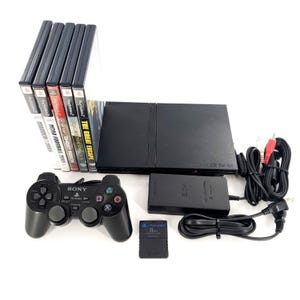 May include: A black Sony PlayStation 2 game console bundle including a black wired controller, an 8MB memory card, a black AC power adapter, AV cables, and five game cases titled Madden 2005, NCAA Football 2005, Ghost Recon, and The Great Escape.