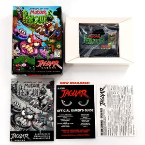 Könnte beinhalten: Atari Jaguar Videospiel Attack of the Mutant Penguins inklusive Originalkarton, in Plastik verpackter Spielkassette, gedrucktem Handbuch, offiziellem Spieleberater-Heft und einer weißen Registrierungskarte mit aufgedrucktem Text.