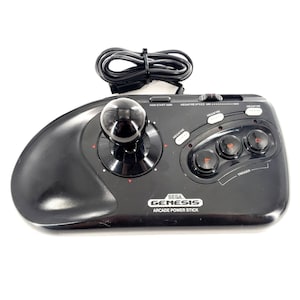 Può includere: Un controller nero Sega Genesis Arcade Power Stick dotato di un joystick centrale con pomello rotondo, tre pulsanti azione circolari etichettati A, B e C, un pulsante start e un cursore per la velocità megafire. Include un cavo nero.