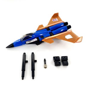 May include: A blue and orange toy jet fighter with black detailing. The toy features a detailed design with wings and a cockpit. Additional black accessories are included, such as two black cylinders, two black blocks, and a small silver piece.