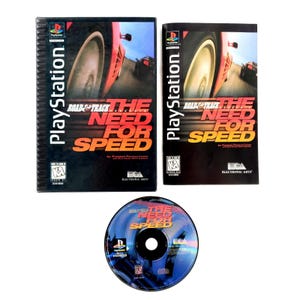 May include: Three items are displayed: two PlayStation game cases and a game disc. The cases feature a red sports car on a track with the game title "ROAD & TRACK THE NEED FOR SPEED." The disc is blue with the game title.
