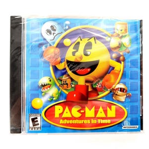 May include: A sealed CD-ROM case for the video game "Pac-Man Adventures in Time." The cover features a yellow Pac-Man character with red boots, surrounded by various cartoon characters on a blue background. The game title is in a red oval.