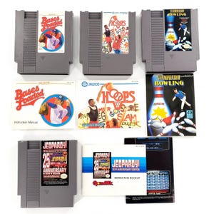 May include: Three grey plastic NES game cartridges and their corresponding instruction manuals for Bases Loaded, Hoops, and Jeopardy! 25th Anniversary Edition, plus a Championship Bowling manual, all featuring colorful game title graphics and artwork.