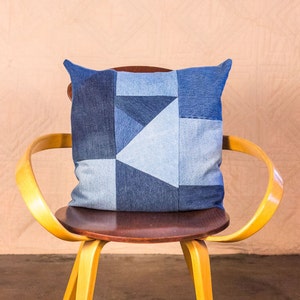 May include: A yellow wooden chair with a brown seat and a blue denim patchwork pillow.