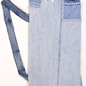 May include: A light blue denim apron with a long strap and a small label that says "Silk Denim".