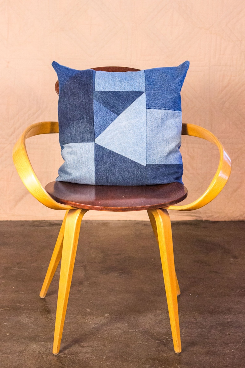 May include: A yellow wooden chair with a brown seat and a blue denim patchwork pillow.