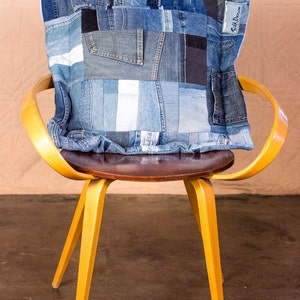 May include: A yellow wooden chair with a brown seat and a blue denim patchwork pillow with the text "Silk Dream" on it.