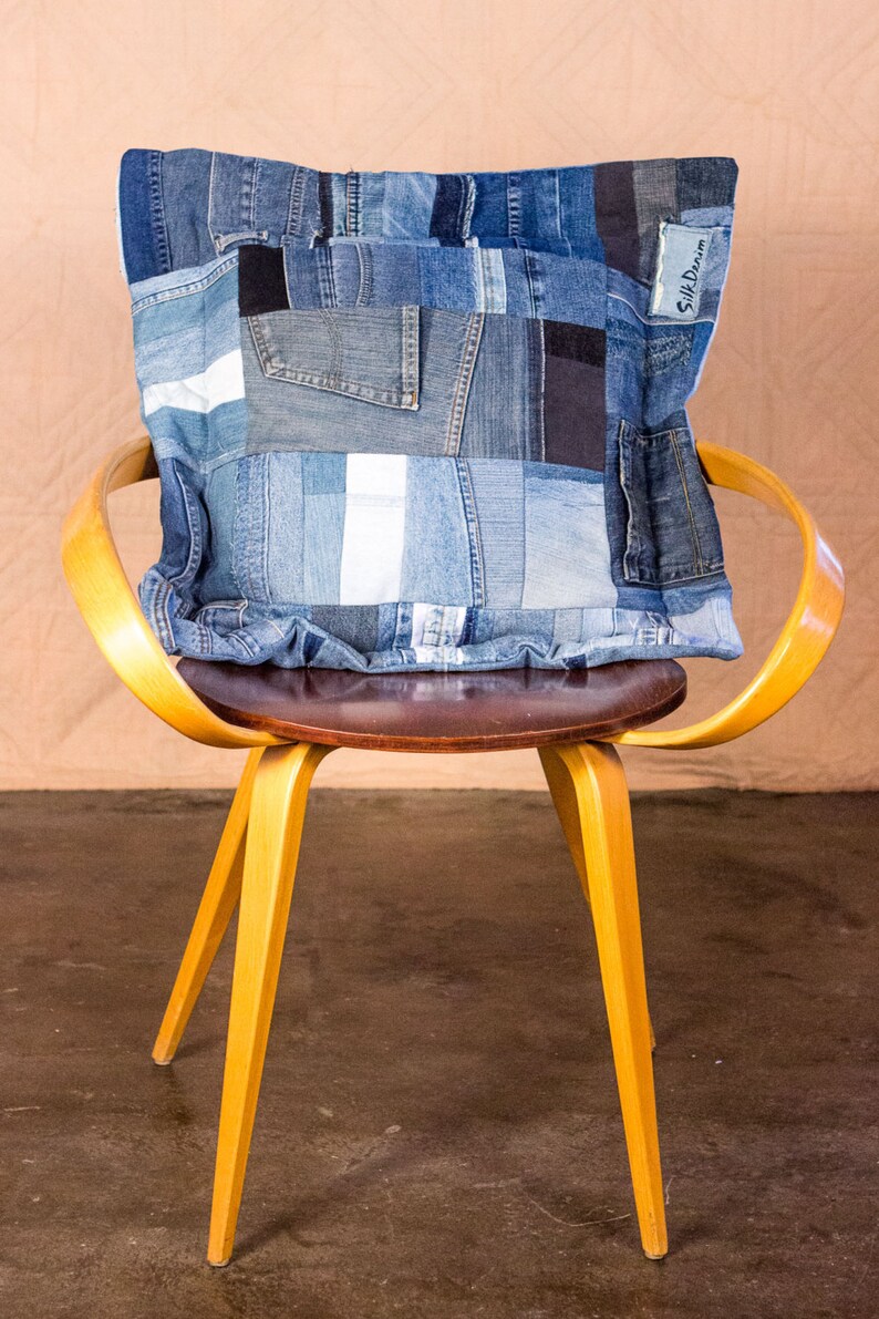 May include: A yellow wooden chair with a brown seat and a blue denim patchwork pillow with the text "Silk Dream" on it.