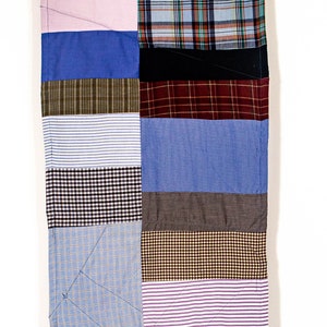 May include: A patchwork quilt made from different patterned fabrics in shades of blue, brown, pink, and white. The quilt is made up of horizontal strips of fabric, each with a different pattern.