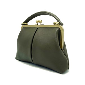 May include: A dark green leather handbag with a gold clasp and a top handle.