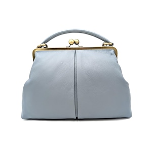 Puede incluir: Un bolso de mano azul claro con superficie texturizada, que presenta un asa superior curva y un cierre de marco de metal en tono lat&oacute;n con dos pomos esf&eacute;ricos. El bolso tiene una forma estructurada con una costura vertical central.