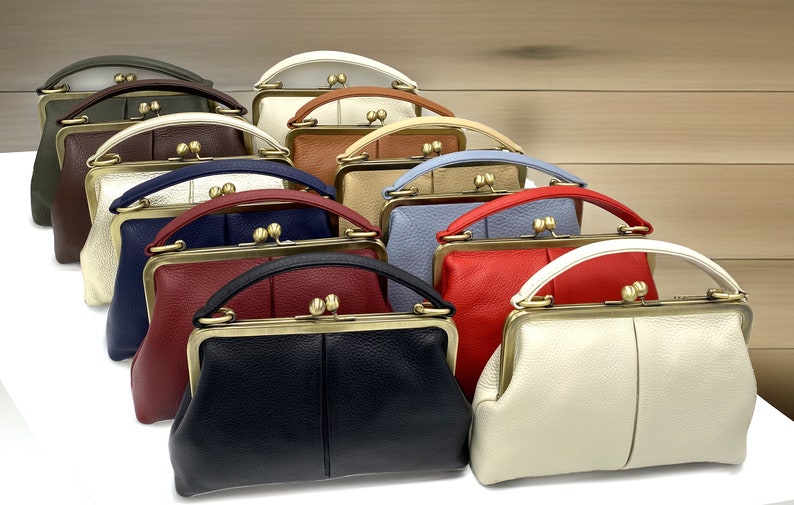 May include: A row of 10 vintage-style purses in various colors, including green, brown, white, red, blue, and cream. Each purse has a unique design and features a gold-toned clasp and handle.