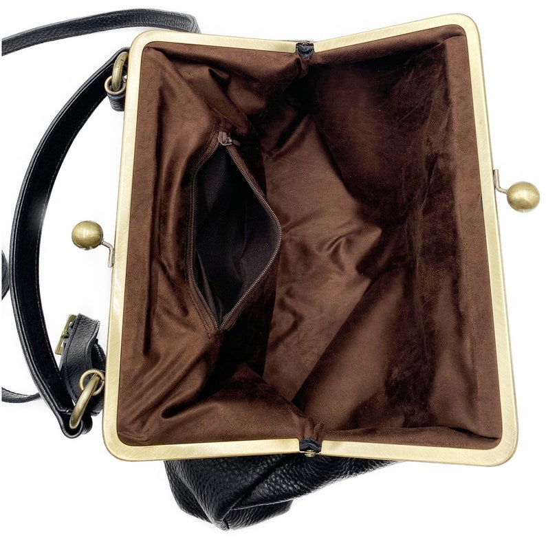 Puede incluir: Un bolso negro con exterior texturizado y un marco de metal dorado con cierre de broche. El interior est&aacute; forrado con tela marr&oacute;n y cuenta con un bolsillo con cremallera. Una correa negra para el hombro est&aacute; sujeta al lateral del bolso.