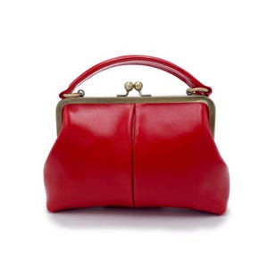 K&ouml;nnte beinhalten: Eine leuchtend rote Handtasche mit einem oberen Griff und einem Kiss-Lock-Verschluss. Die Tasche hat eine strukturierte Form und ein gl&auml;nzendes Finish. Die Hardware ist goldfarben. Die Tasche ist ein klassischer Stil, geeignet f&uuml;r verschiedene Anl&auml;sse.