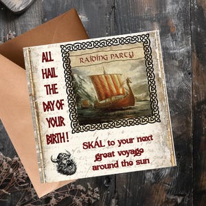 May include: A square greeting card with a brown envelope featuring a Viking longship illustration, a Celtic knot border, and the text: ALL HAIL THE DAY OF YOUR BIRTH! RAIDING PARTY, SKÁL to your next great voyage around the sun, and a Viking head icon.