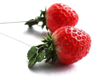 May include: A pair of earrings featuring red strawberry charms with green leaves, hanging from silver wires.
