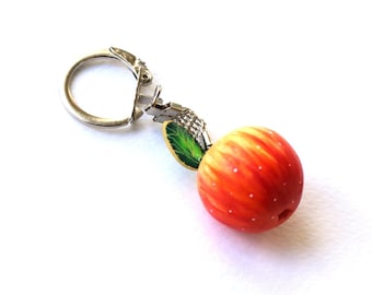 May include: A silver-toned metal charm featuring a spherical peach-coloured fruit with subtle red gradients and tiny white dots. The charm includes a small green leaf with dark veins and is attached to a circular metal ring for easy attachment.