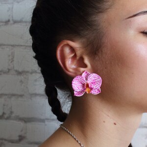 May include: A pair of pink and white orchid earrings. The earrings are made of polymer clay and have a realistic look.