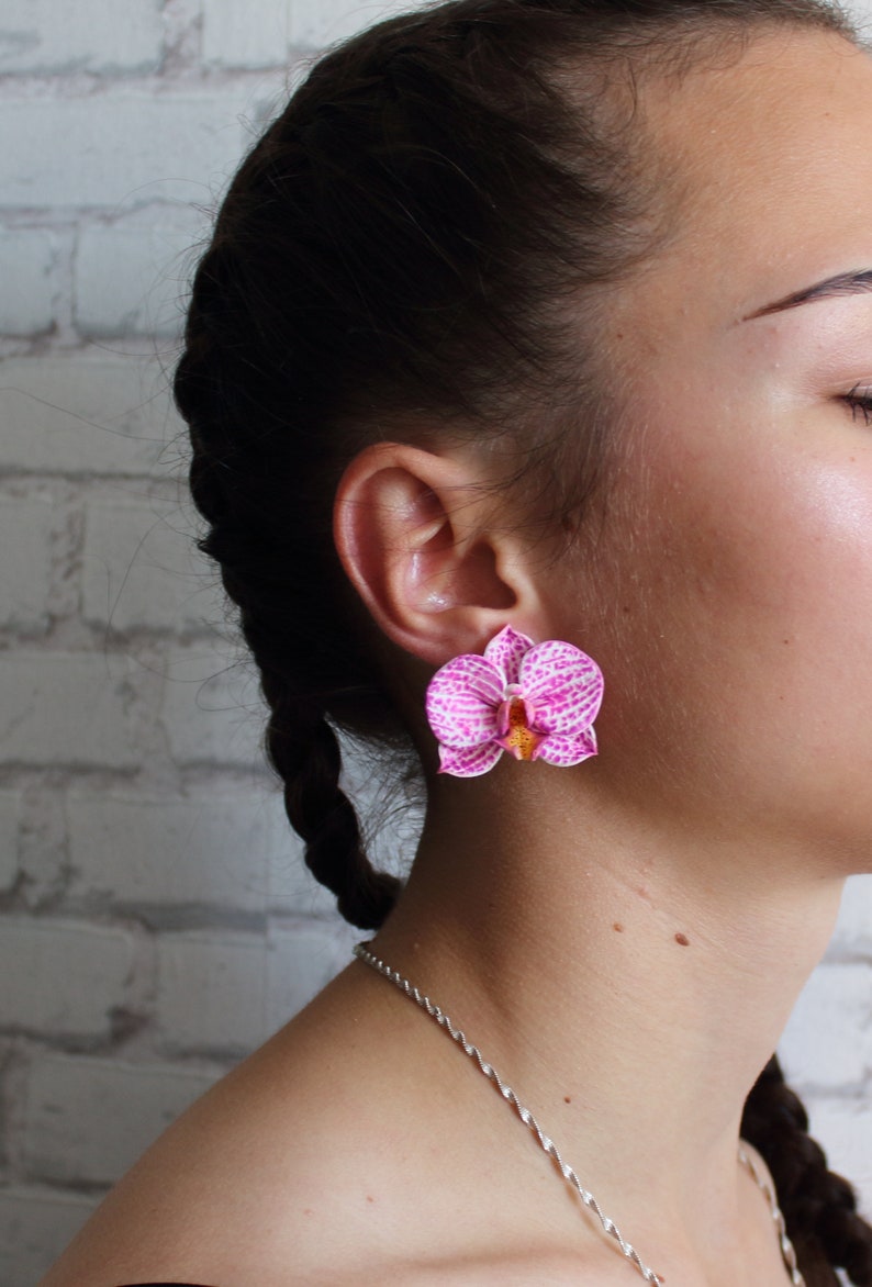 May include: A pair of pink and white orchid earrings. The earrings are made of polymer clay and have a realistic look.