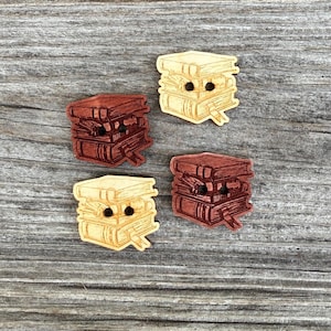 May include: Four wooden buttons with a stack of books design. Two buttons are light brown with a dark brown design and two buttons are dark brown with a light brown design.