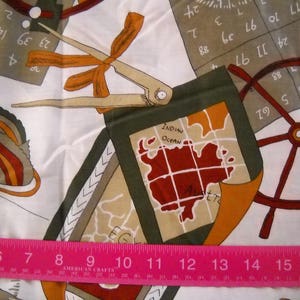 May include: A white fabric with a colorful design featuring a map of the Indian Ocean, a compass, a ruler, and a ship's wheel. The fabric has a brown, red, and blue color scheme.