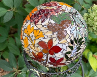 Mosaic gazing globe with fall leaves and winter foliage and berries