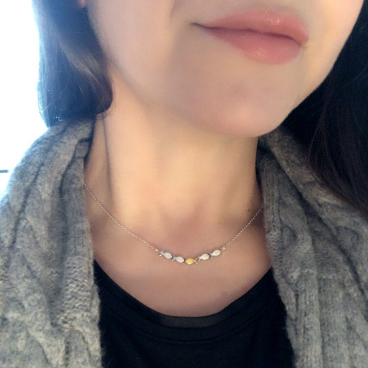 Swimming against the current. Dainty silver necklace. School of fish with one golden enameled fish swimming upstream. Gift for her.