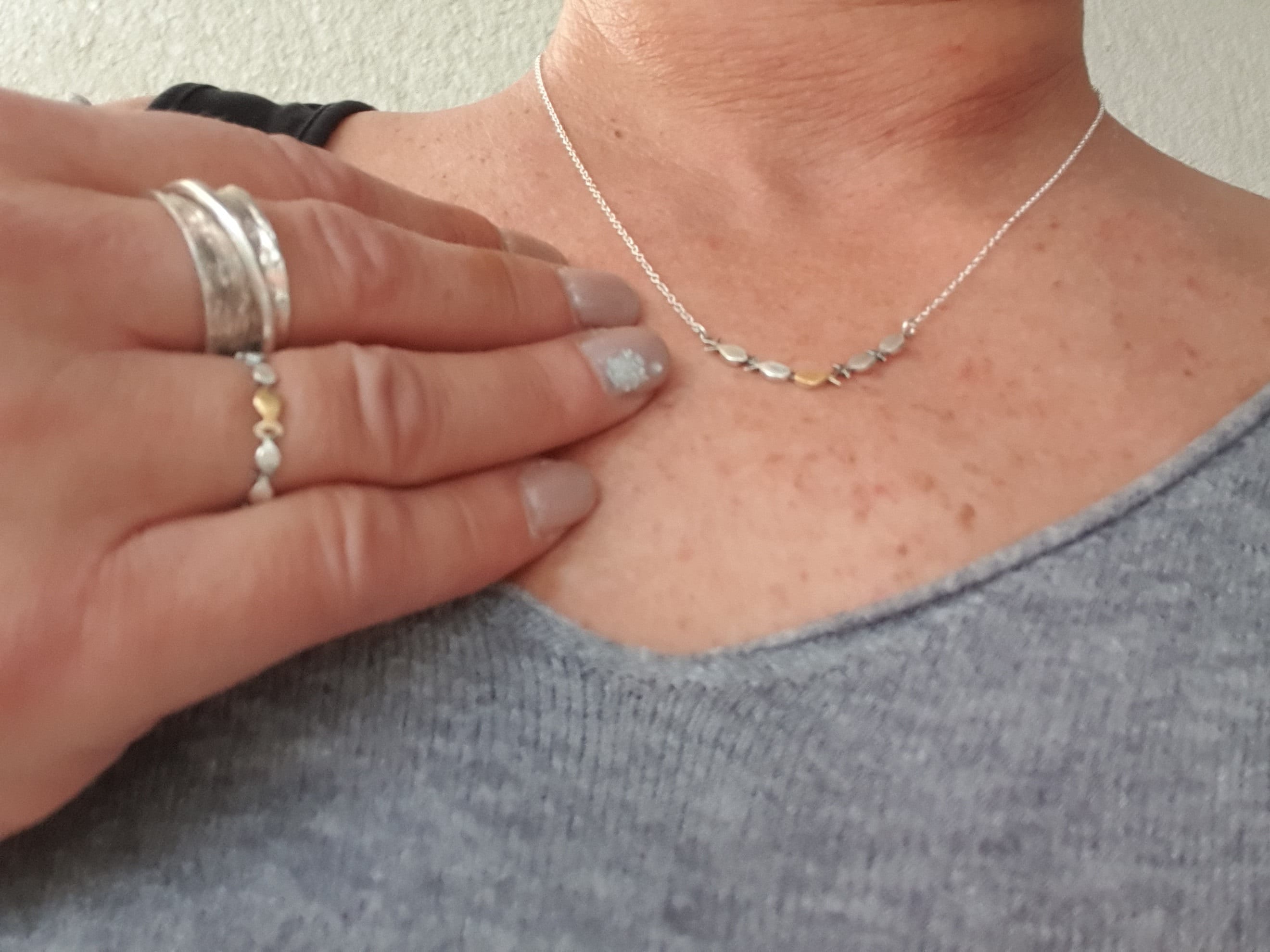 Swimming against the current. Dainty silver necklace. School of fish with one golden enameled fish swimming upstream. Gift for her.