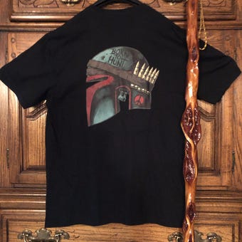 Distressed Bounty Hunter Helmet graphic T-shirt displayed on wood