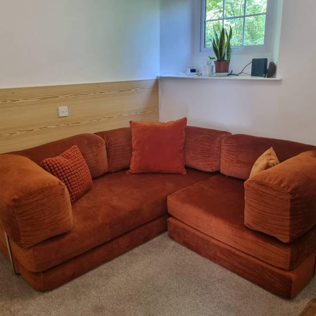 Rust corduroy corner sectional with matching cushions in a bright room, photographed by the buyer