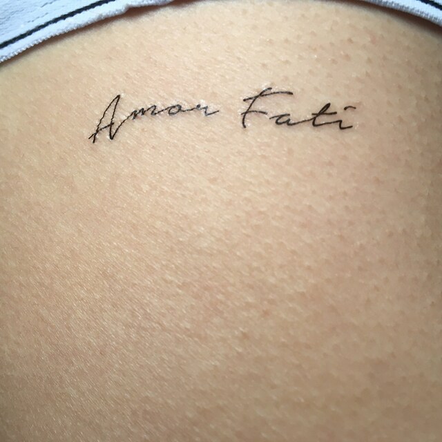 Amor Fati lettering tattoo on the inner forearm
