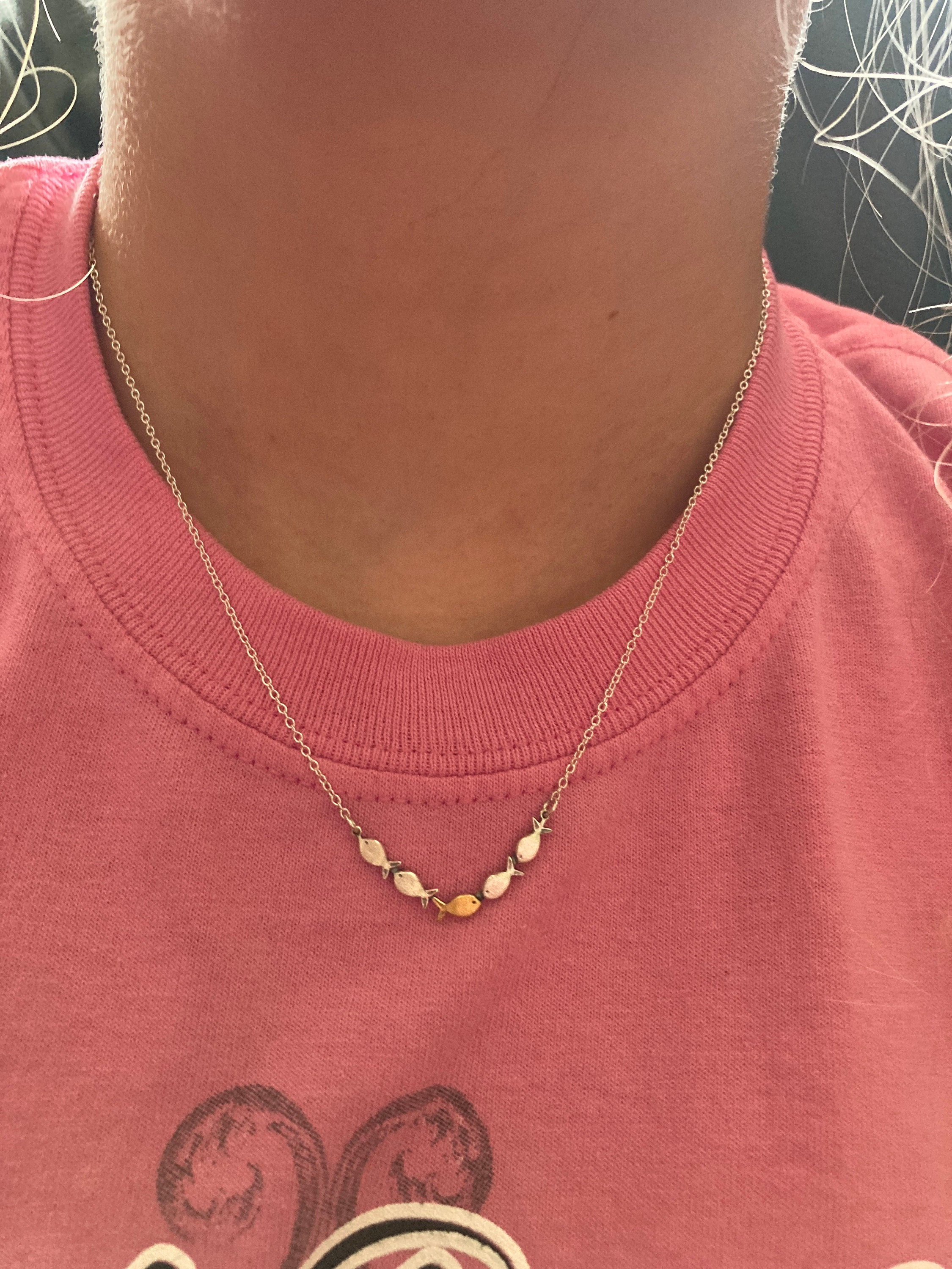 Swimming against the current. Dainty silver necklace. School of fish with one golden enameled fish swimming upstream. Gift for her.