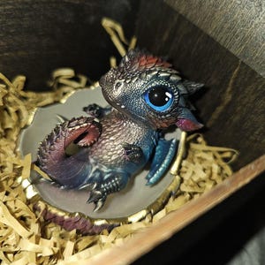 ドラゴンの孵化、卵の殻に入ったかわいい新生児ドラゴン、濃い虹色の
